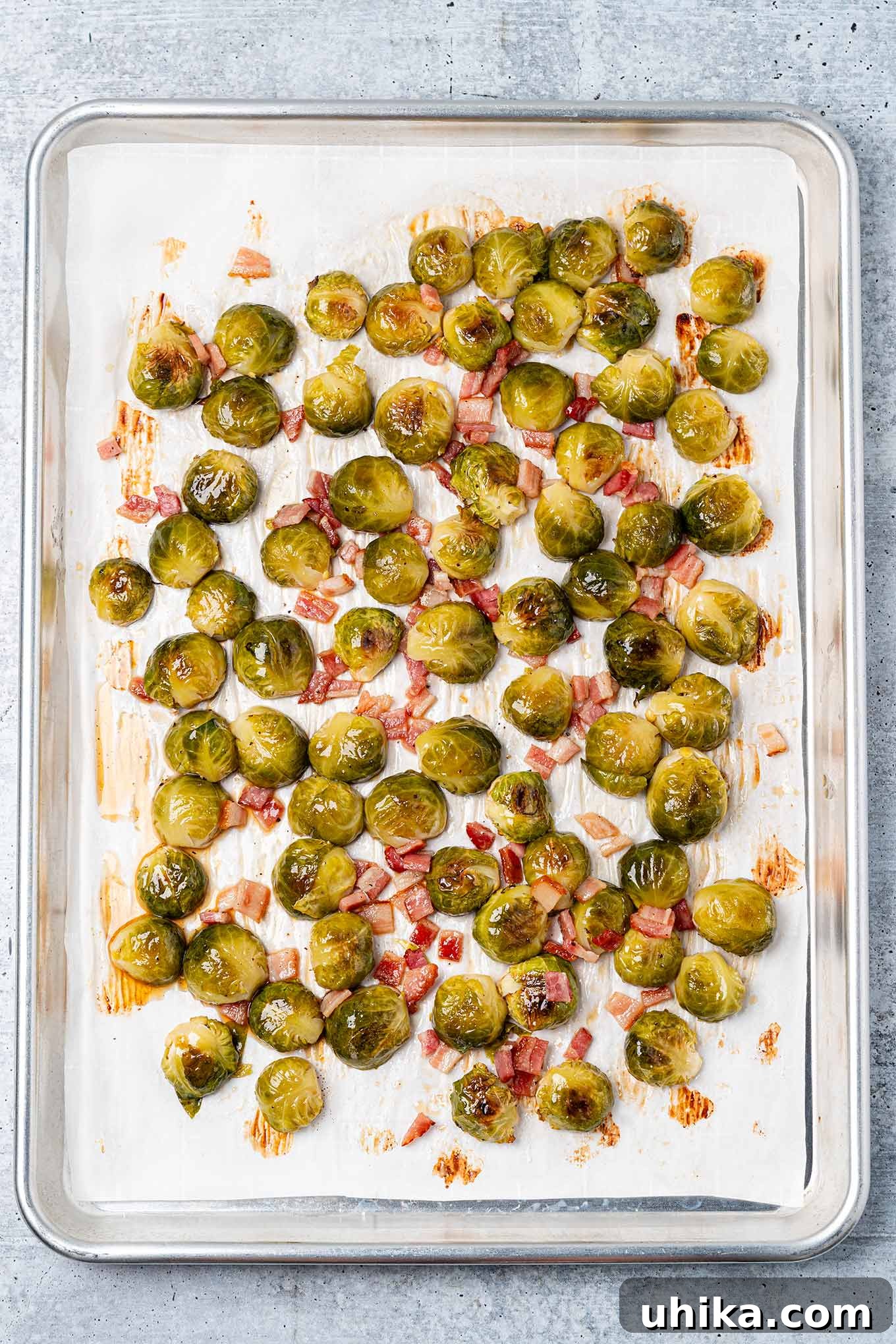 Sticky Maple Bacon Brussels Sprouts 4 Maple glazed Brussels sprouts and bacon on a baking sheet ready to be turned and finish roasting.