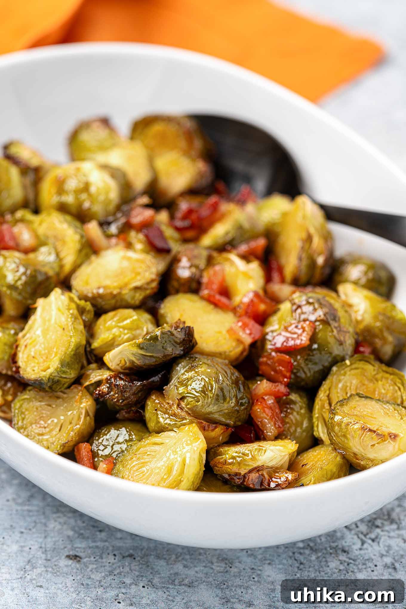 Sticky Maple Bacon Brussels Sprouts 6 Roasted maple glazed Brussels sprouts with bits of bacon in a white serving bowl.