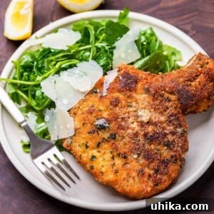 Crispy Milanese Pork Chops 4 Close-up of a golden-brown Pork Chop Milanese with a crispy crust, garnished with fresh herbs.