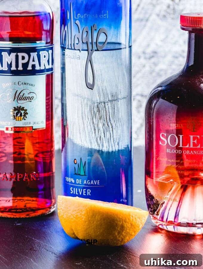 Campari Kissed Tequila Orange Margarita 3 A bottle of Campari, bottle of tequila, bottle of Solerno blood orange liquor and half an orange.