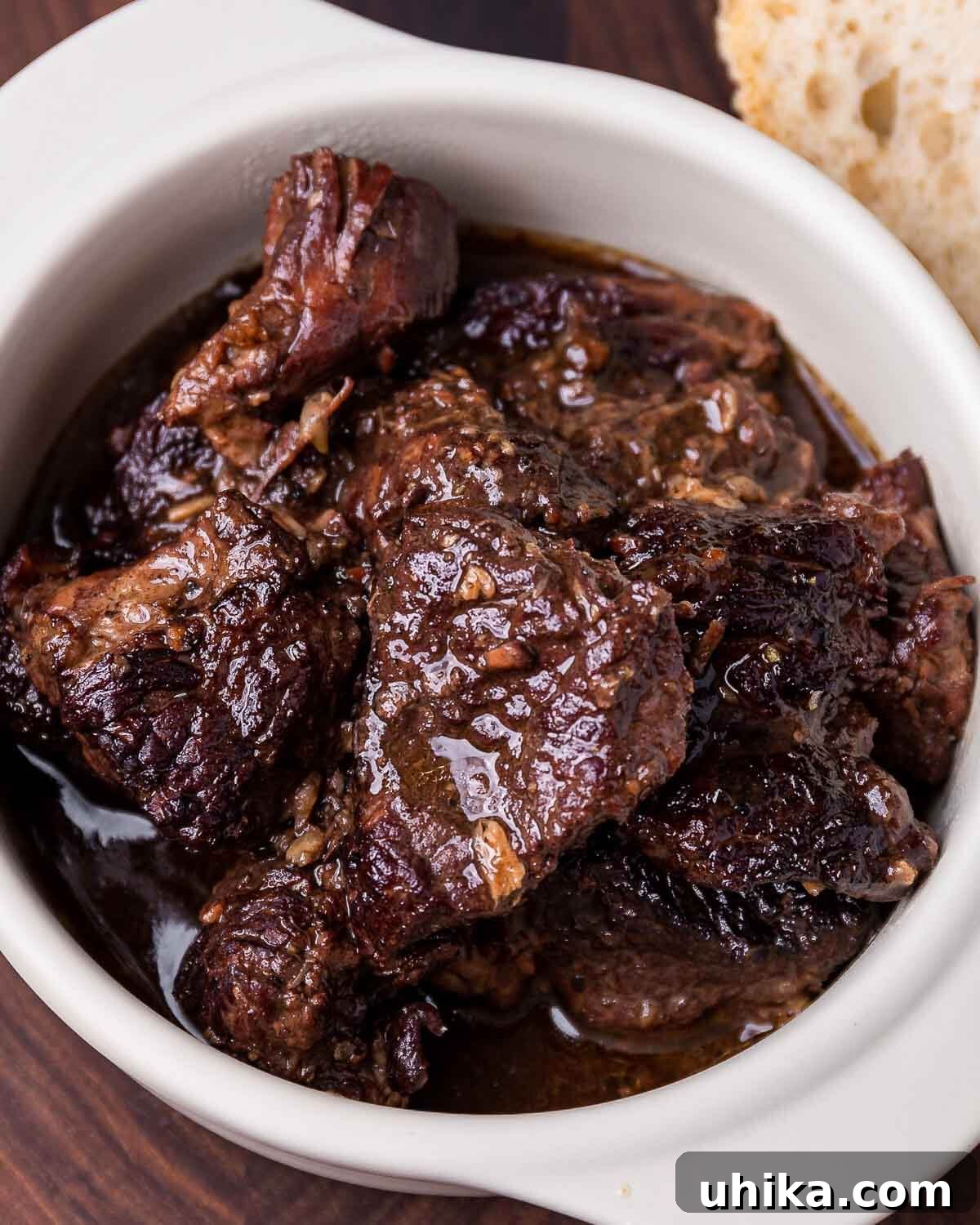 Tuscan Peppery Beef 6 A close-up view of Peposo, a Tuscan beef and black pepper stew, served in a white bowl with a rich, dark sauce and tender chunks of beef.