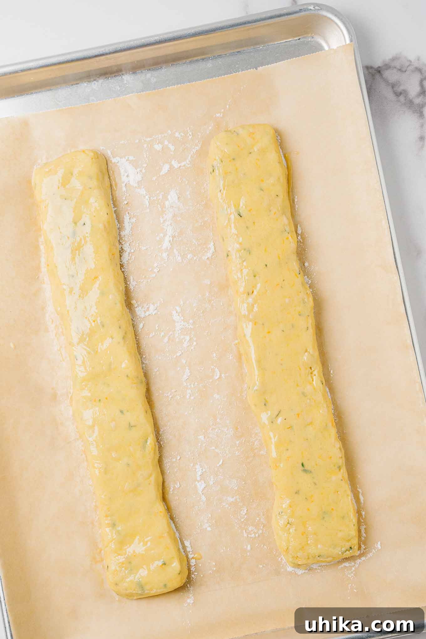 Zesty Butter Biscotti: A Double Treat 4 Two logs of orange biscotti dough, ready for their first bake, on a parchment-lined baking sheet.