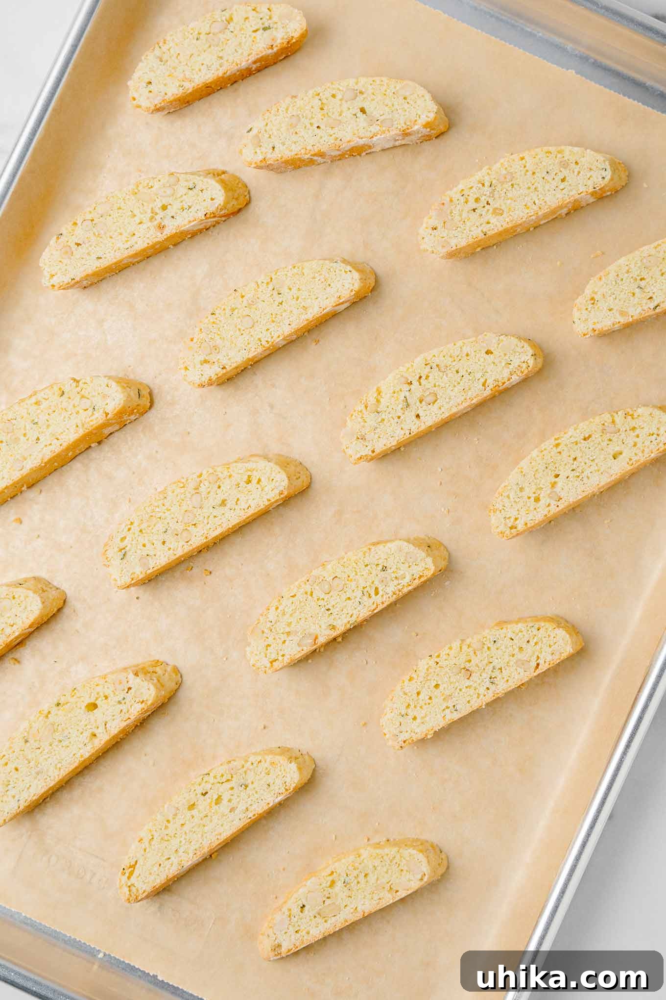 Zesty Butter Biscotti: A Double Treat 6 Golden brown American-style biscotti, made with butter, resting on a parchment-lined baking sheet after their second baking cycle.