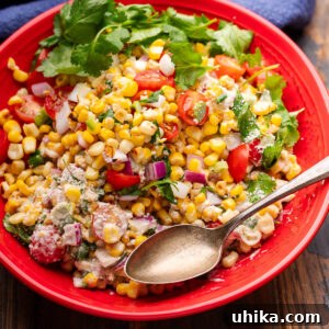Mexican street corn salad in red bowl with cilantro garnish.
