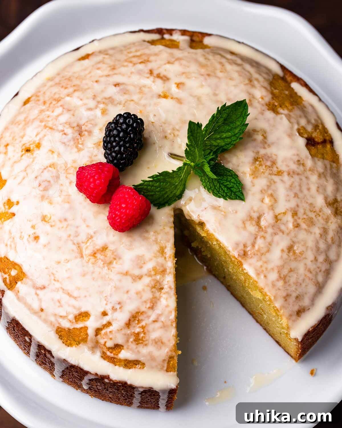 Overhead shot of cut olive oil cake on white cake stand.