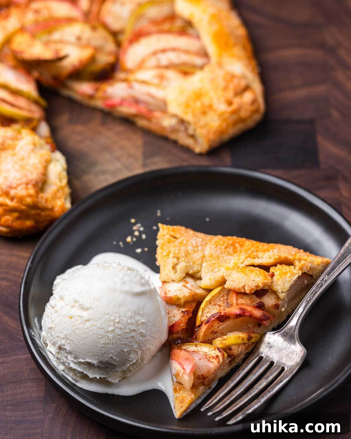 Rustic Apple Galette 9 Slice of apple crostata and vanilla ice cream in black plate on walnut cutting board.