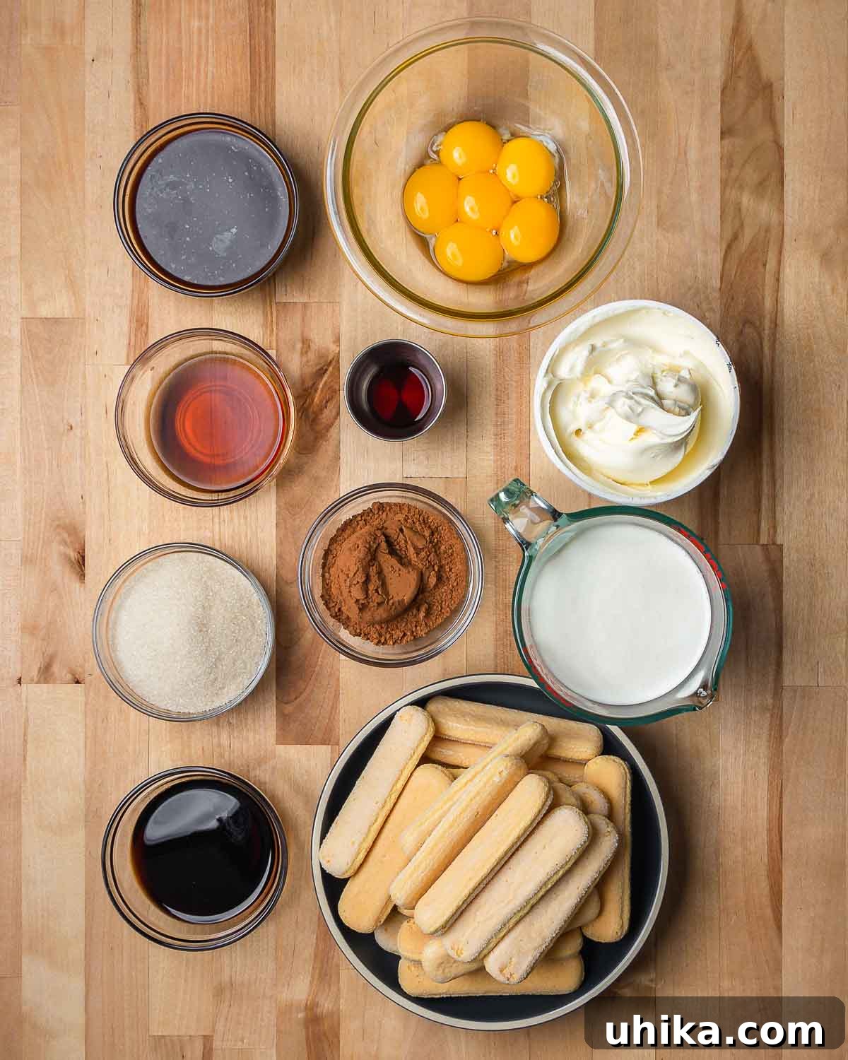 Tiramisu The Uplifting Dessert 3 A vibrant flat lay showcasing all the fresh ingredients required for a classic Tiramisu recipe. Espresso, golden egg yolks, fragrant vanilla extract, sweet Marsala wine, creamy mascarpone, rich cocoa powder, a bottle of coffee liqueur, heavy cream, granulated sugar, and delicate ladyfinger cookies are neatly arranged.