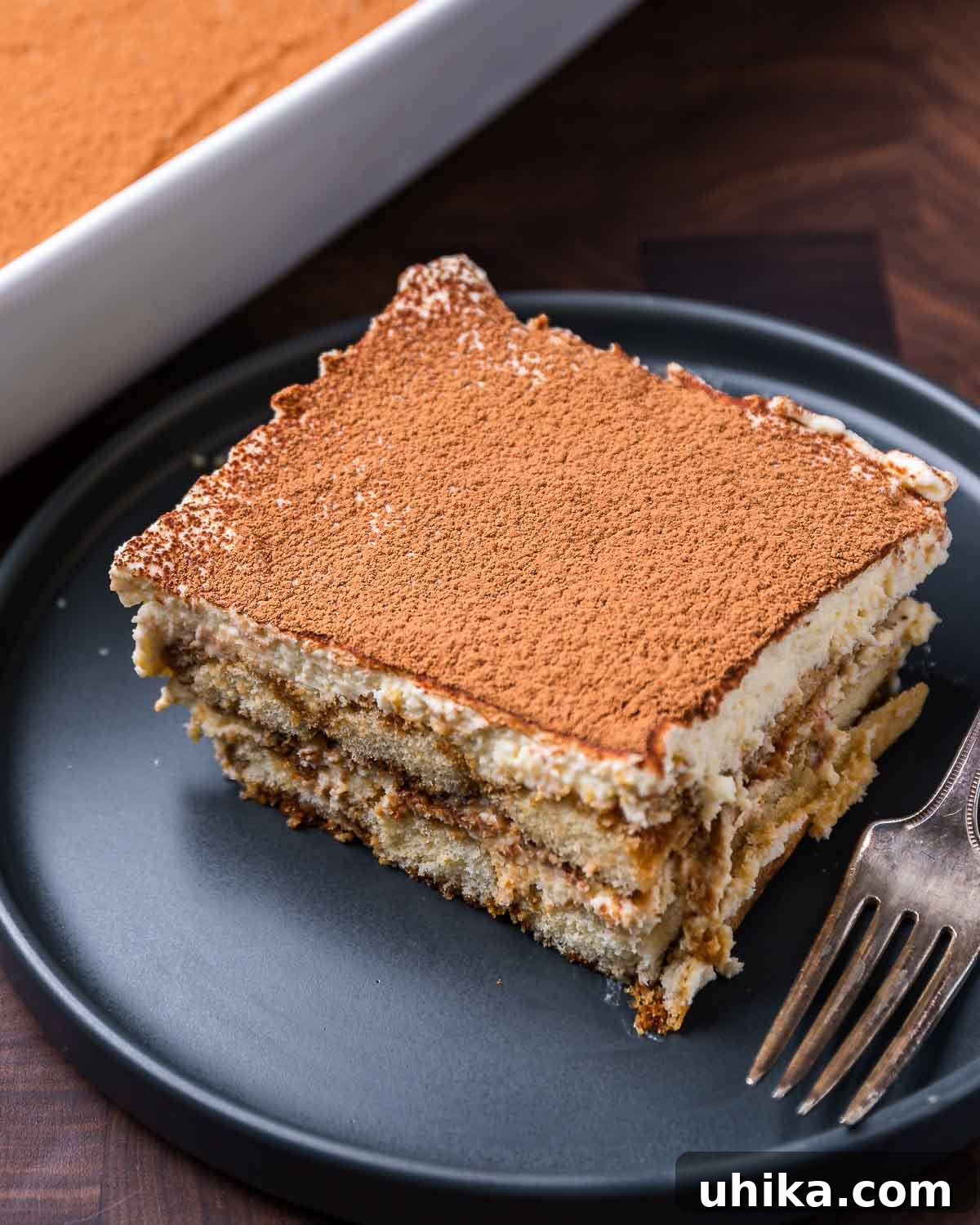 Tiramisu The Uplifting Dessert 9 A large, inviting piece of Tiramisu, artfully presented on a deep blue plate, highlighting its rich, layered composition.