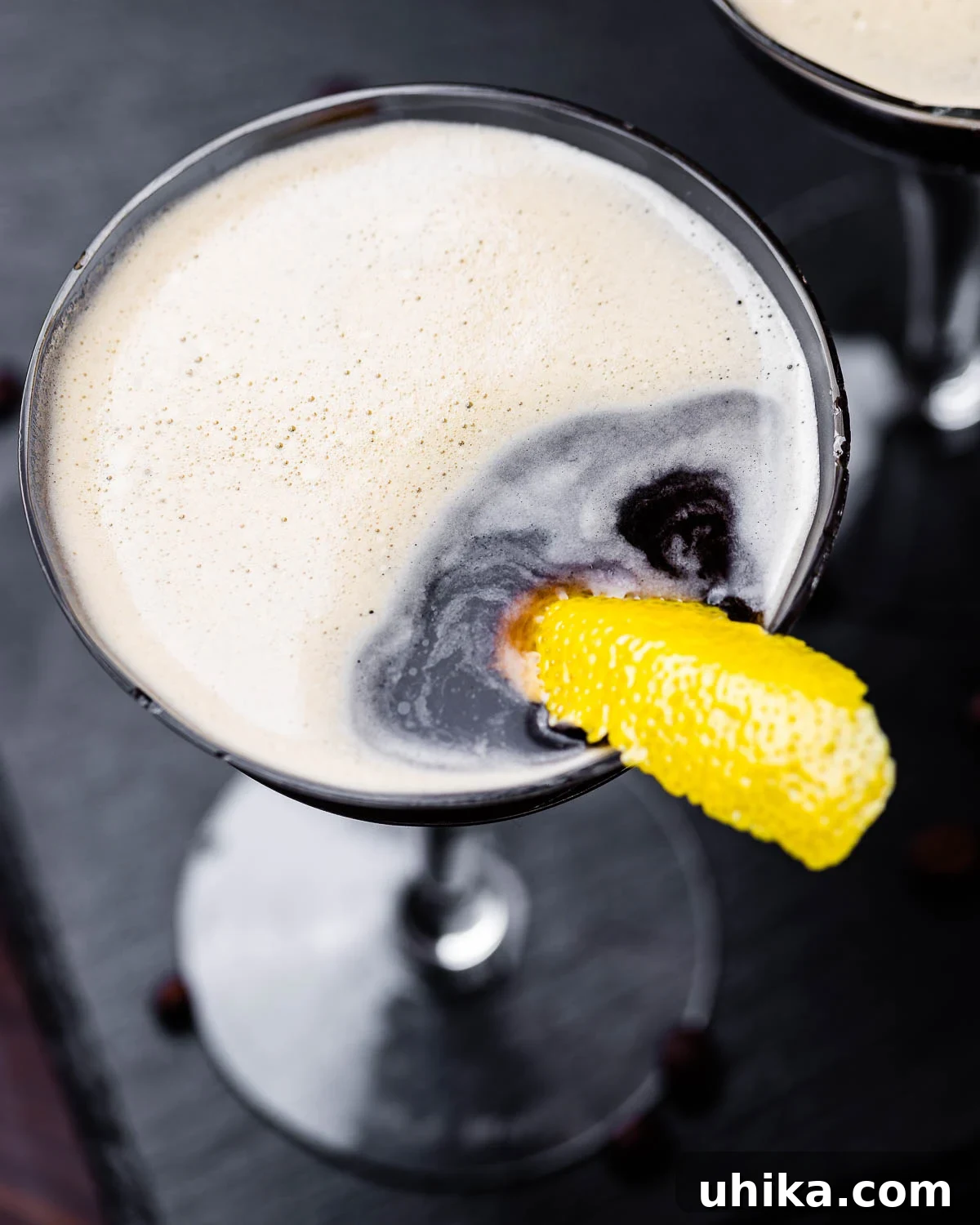 Velvet Nightcap 4 Overhead shot of a single espresso martini on a black slate board, garnished with a lemon peel.