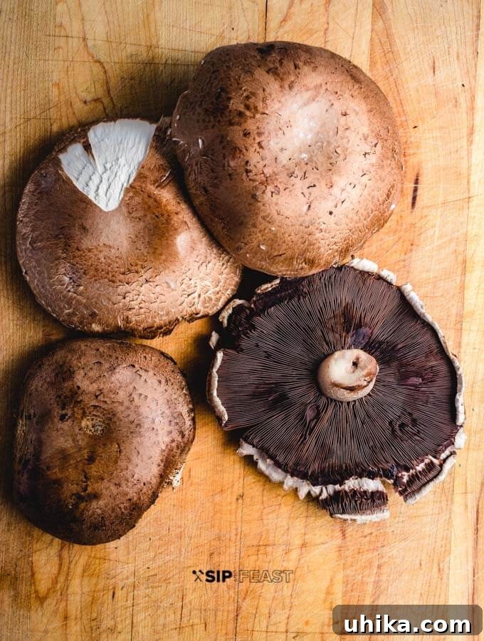 Cleaning portobello mushrooms for baking. Large portobello mushrooms laid out on a wooden cutting board, ready for cleaning and preparation.