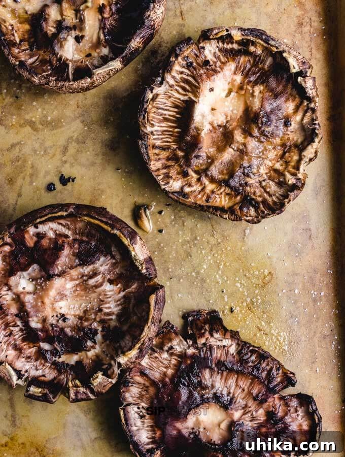 Partially baked portobello mushrooms ready for bruschetta filling. Baked portobello mushrooms removed from the oven, showing slight browning and released moisture.