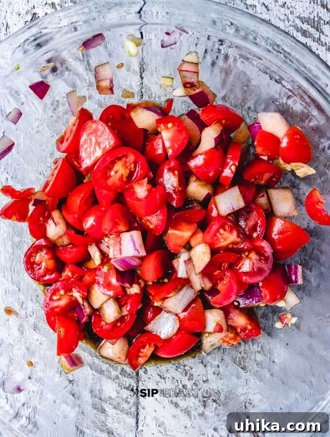 Balsamic bruschetta mixture ready. Chopped tomatoes, red onions, and garlic mixed in a bowl, forming the bruschetta mixture.