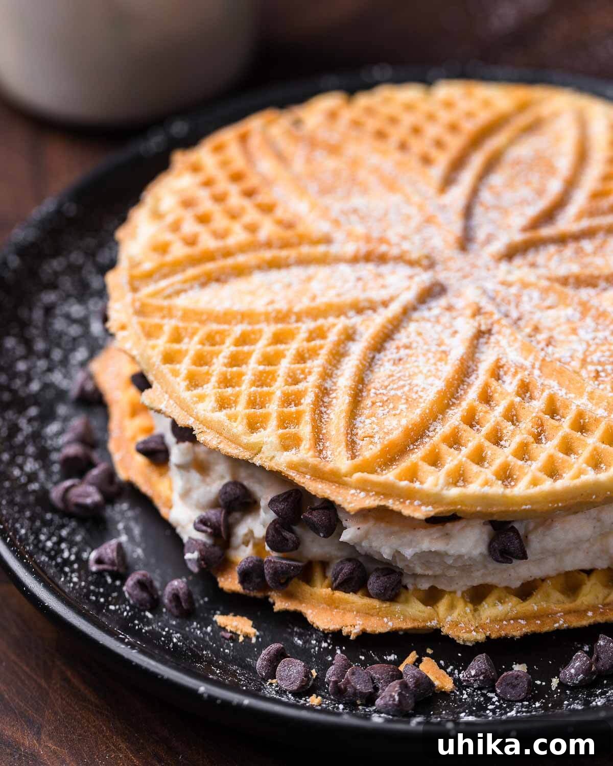 Crisp Italian Delights 9 Pizzelle sandwich with cannoli cream on black plate, illustrating a rich, layered dessert option.