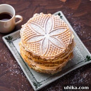 Pizzelle recipe featured image, showcasing a stack of golden, intricately patterned cookies.