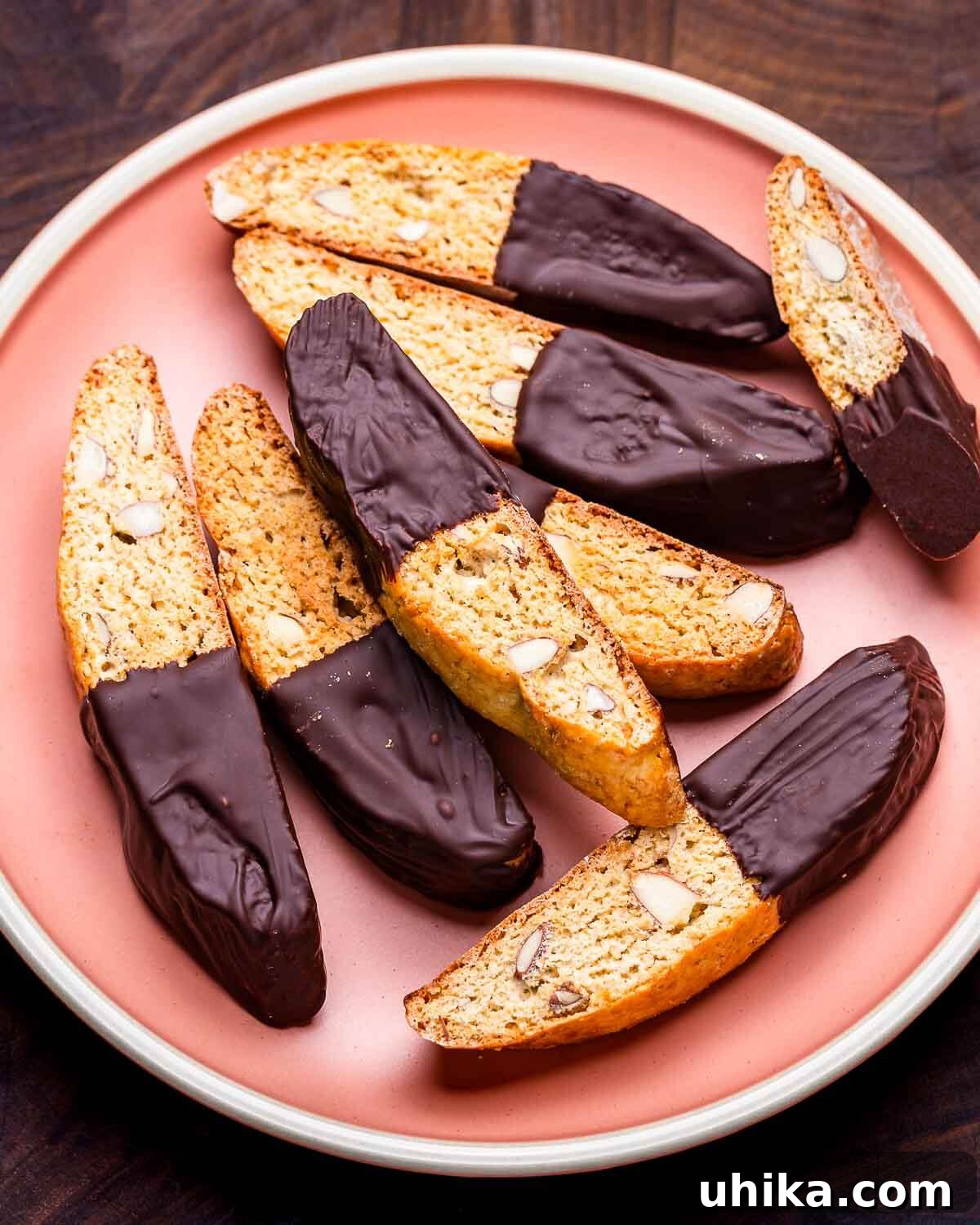 Twice-Baked Almond Delights 2 Almond biscotti with chocolate in pink plate on walnut cutting board.
