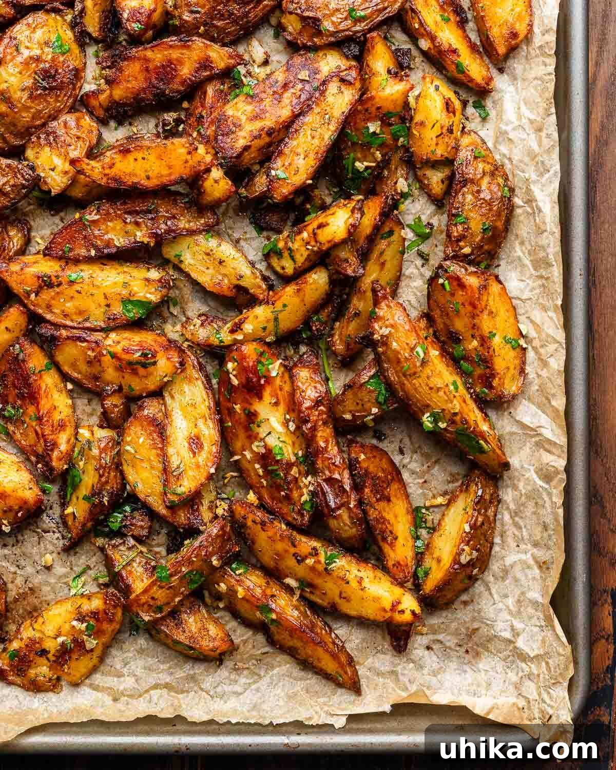 Golden Garlic Lemon Roasters 2 Cripsy roasted potatoes topped with garlic and herbs on brown parchment paper, glistening and golden.