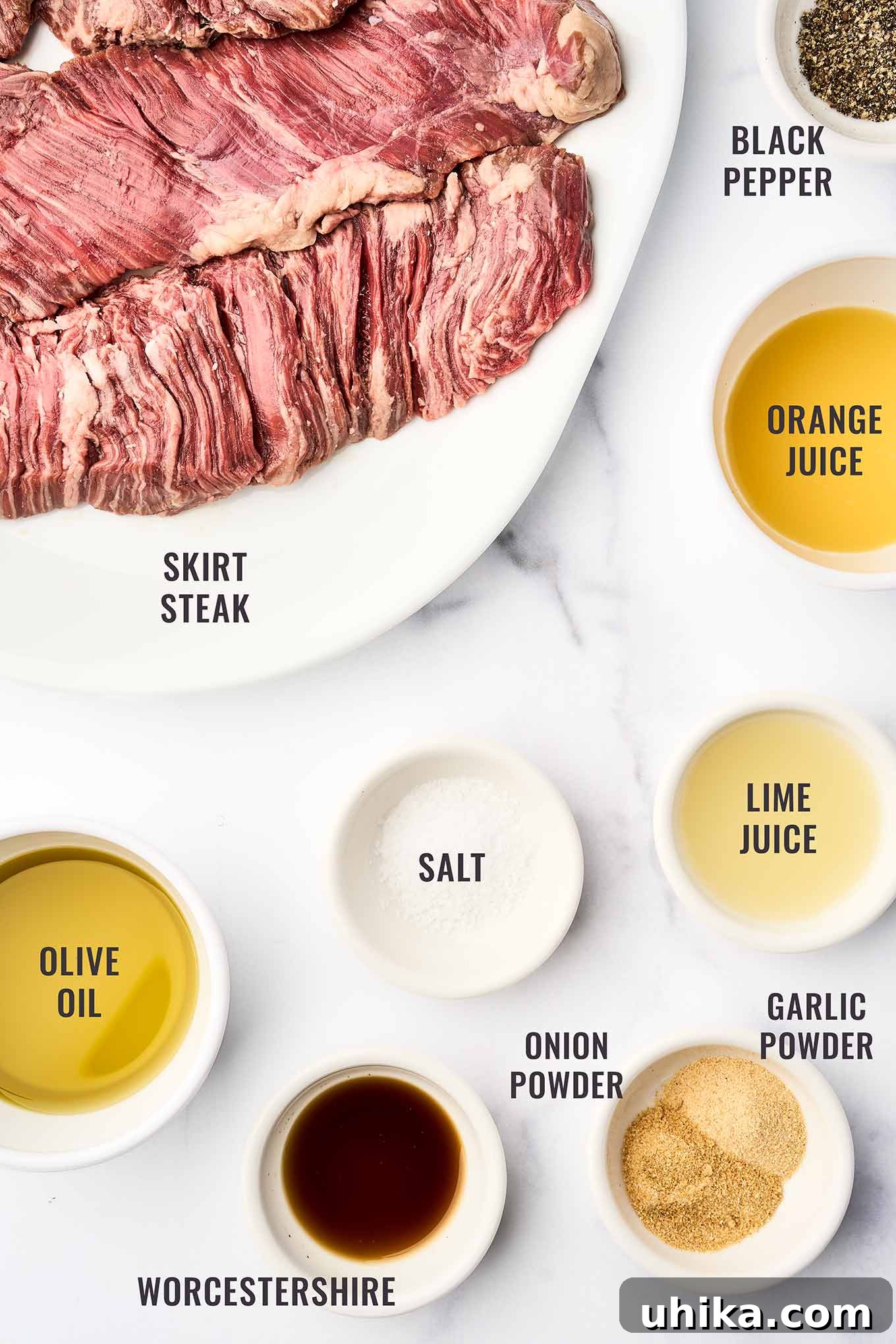 Sizzling Steak, Vibrant Chimichurri 3 A labeled, overhead view of the marinade ingredients for grilled skirt steak ingredients including skirt steak, orange juice, lime juice, olive oil, Worcestershire sauce, garlic powder, onion powder, salt, and black pepper.