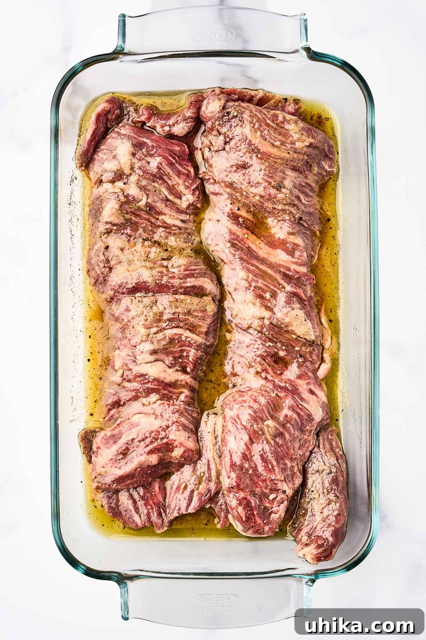 Sizzling Steak, Vibrant Chimichurri 4 Raw skirt steak marinating in a glass dish with olive oil, orange and lime juice, and seasonings - the first step for making grilled skirt steak with chimichurri sauce.