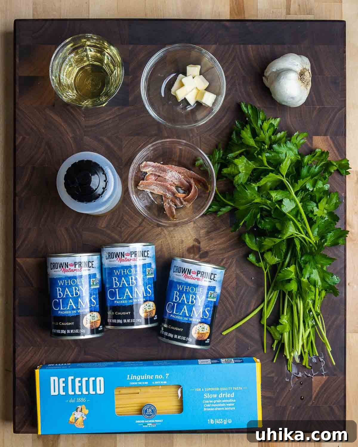 Easy Weeknight Clam Linguine 5 Ingredients shown: white wine, butter, garlic, olive oil, anchovies, parsley, canned clams, and linguine.
