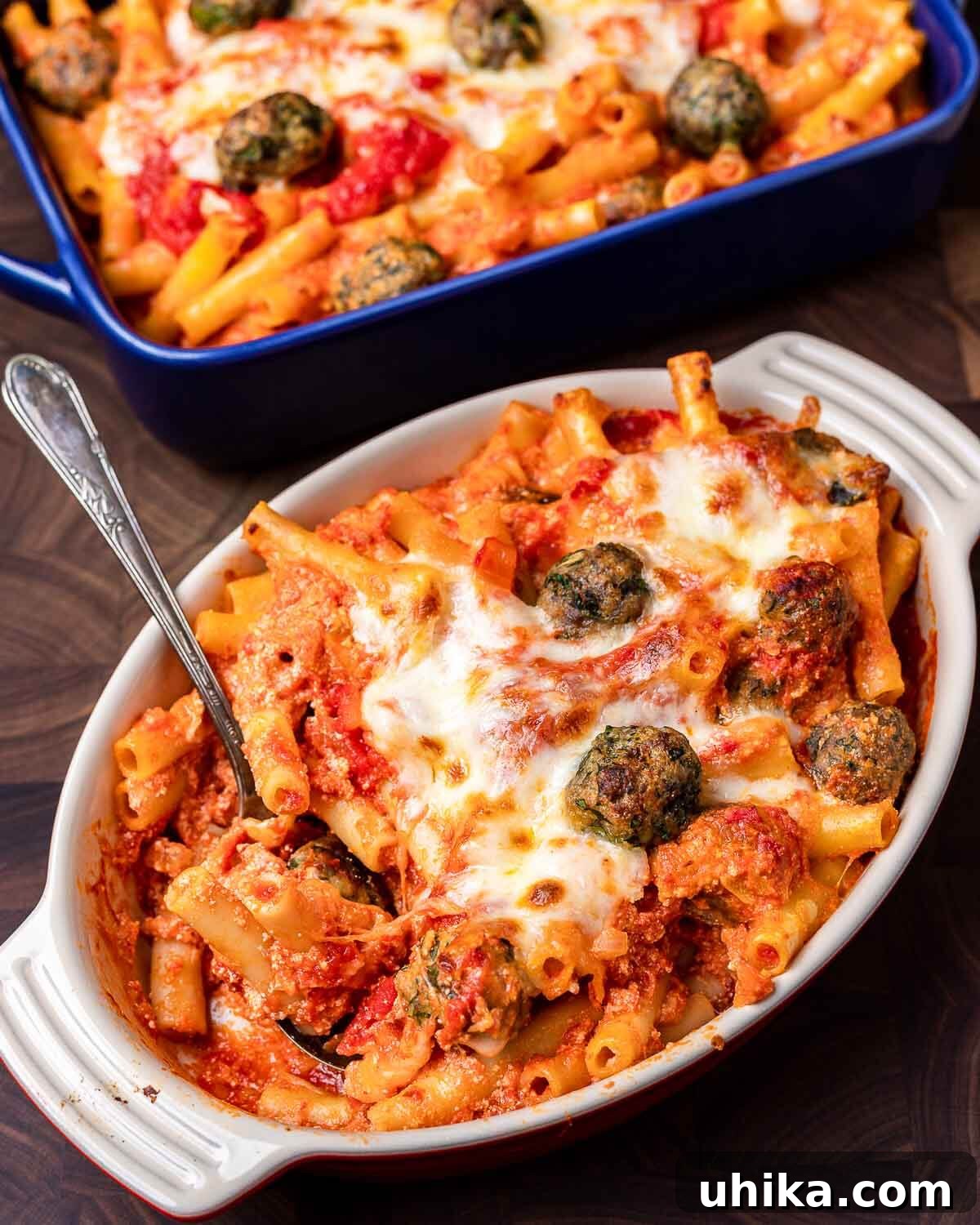 Cheesy Meatball Ziti Bake 8 Baked ziti with tiny meatballs displayed beautifully in two separate baking dishes, resting on a rustic walnut cutting board.