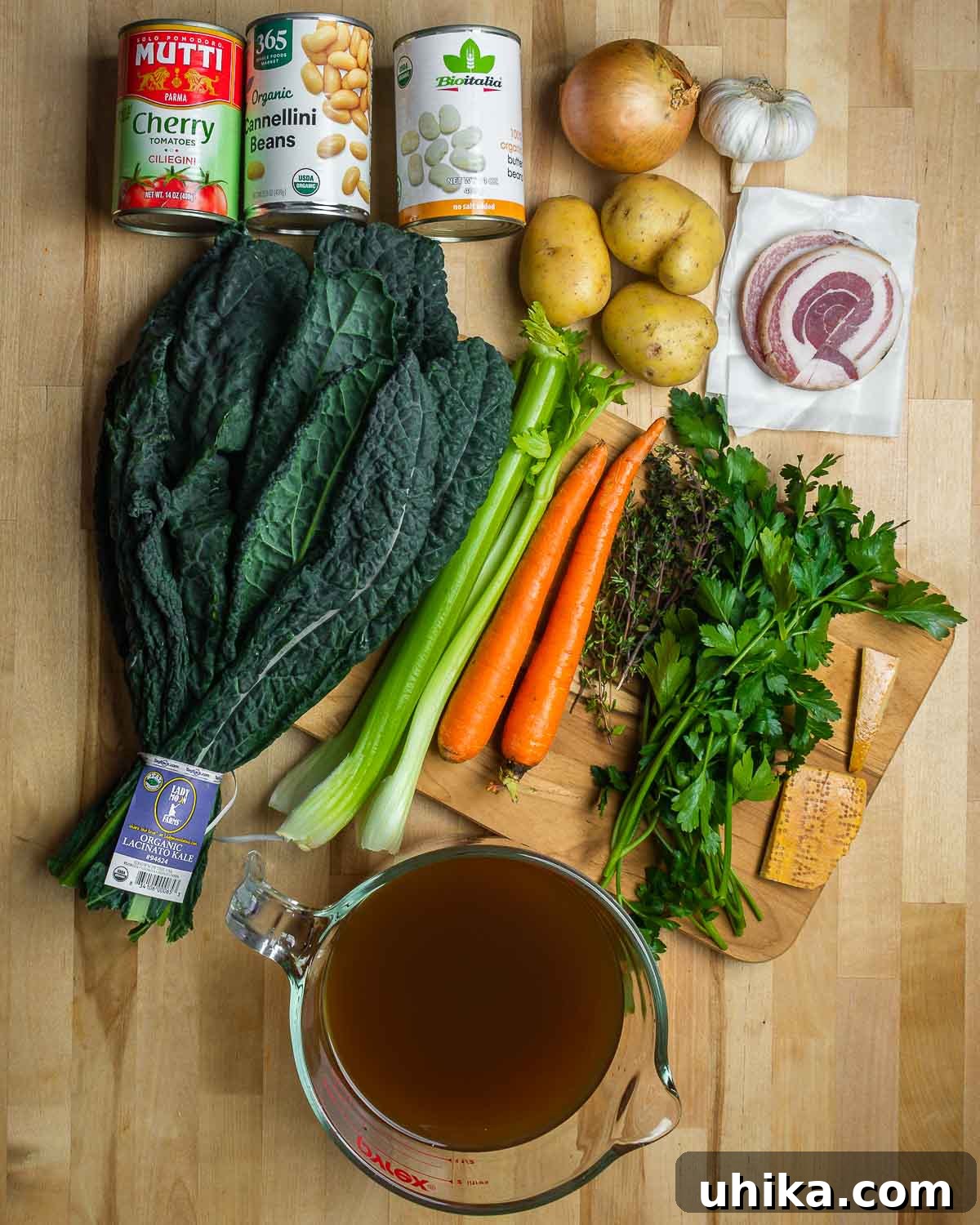 Hearty Vegetable Minestrone 3 Ingredients shown: tomatoes, beans, onion, garlic, potatoes, pancetta, kale, celery, carrota, herbs, parmesan rinds, and vegetable stock.