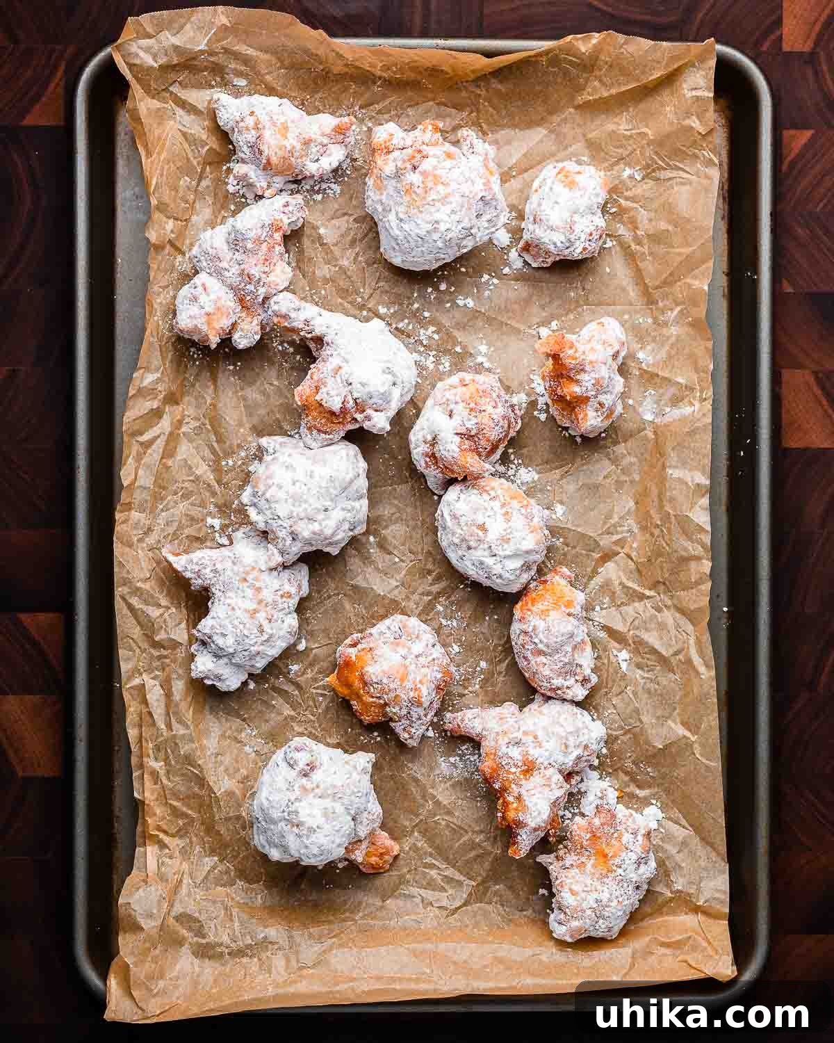 Italian Doughnut Delights 10 Overhead shot of fried zeppole on parchment paper lined baking sheet.