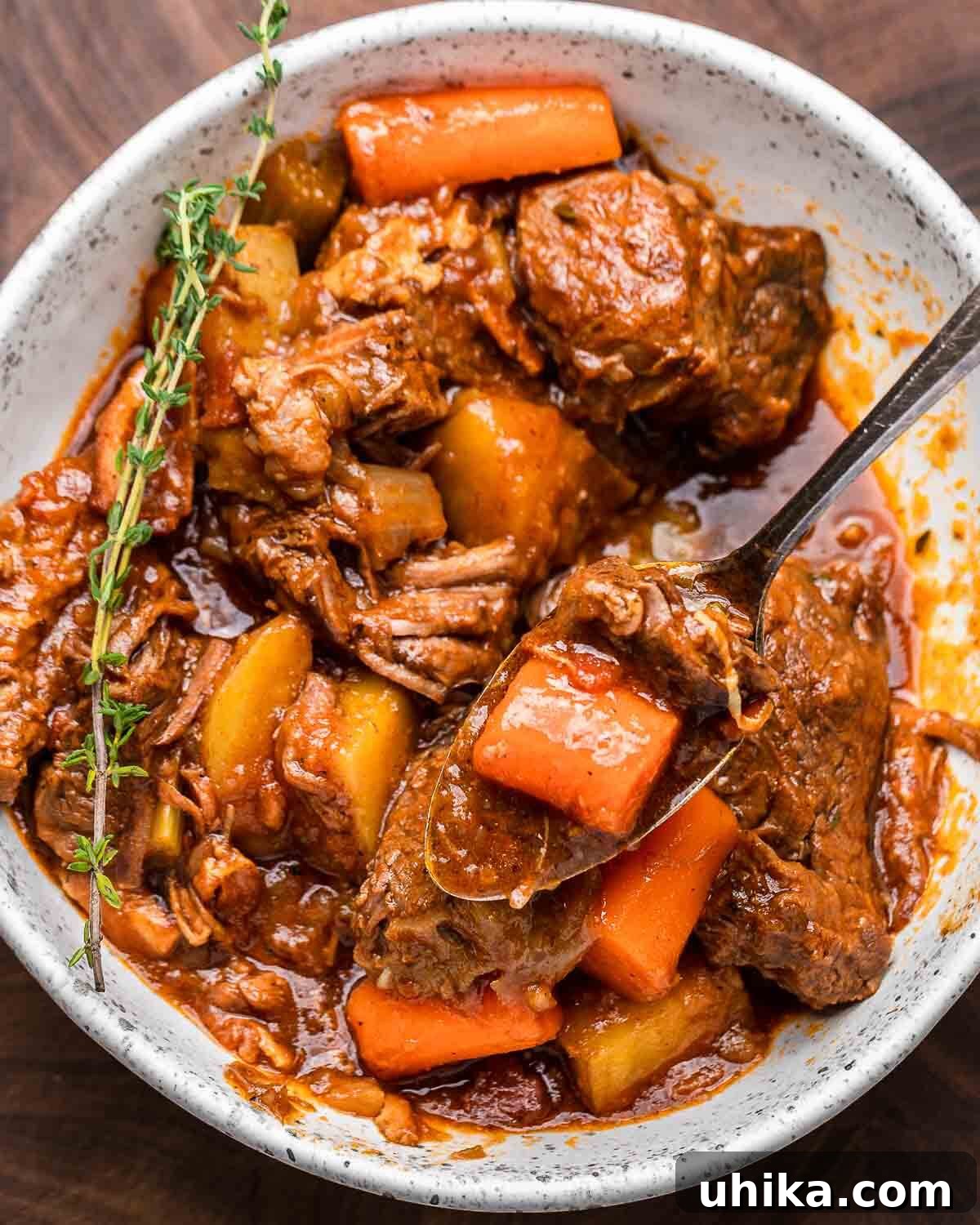 Rich Guinness Beef Stew 2 Ovehead shot of Guinness beef stew in white bowl with thyme garnish, ready to be served.