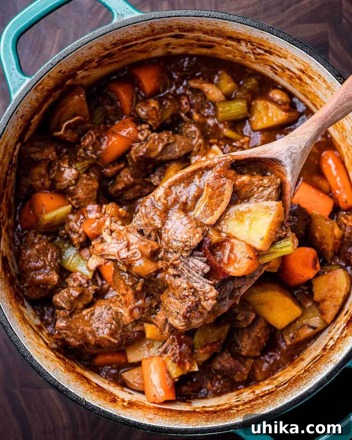 Rich Guinness Beef Stew 10 Overhead shot of Guinness beef stew in a vibrant blue Dutch oven with a rustic wooden ladle, steaming hot and ready to serve.