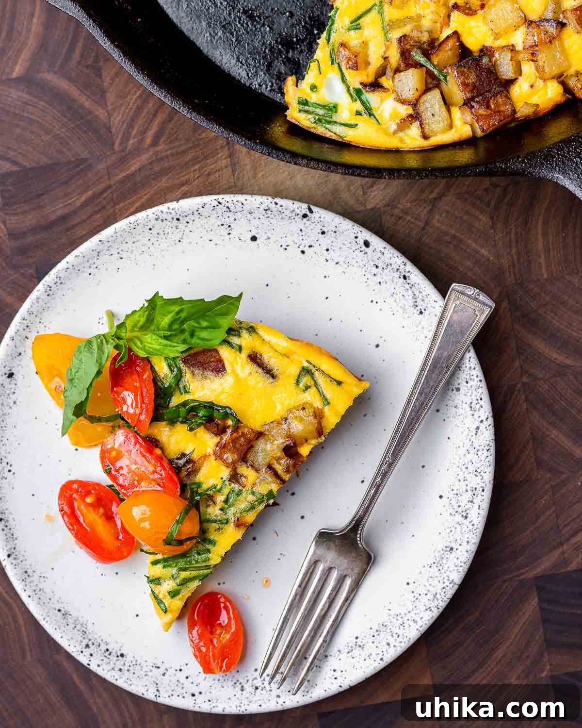 Rustic Potato and Egg Bake 2 A perfectly cooked slice of potato frittata, topped with vibrant cherry tomatoes and fresh herbs, presented on a white plate, highlighting its golden-brown crust and fluffy interior. Ideal for an Italian-inspired meal.