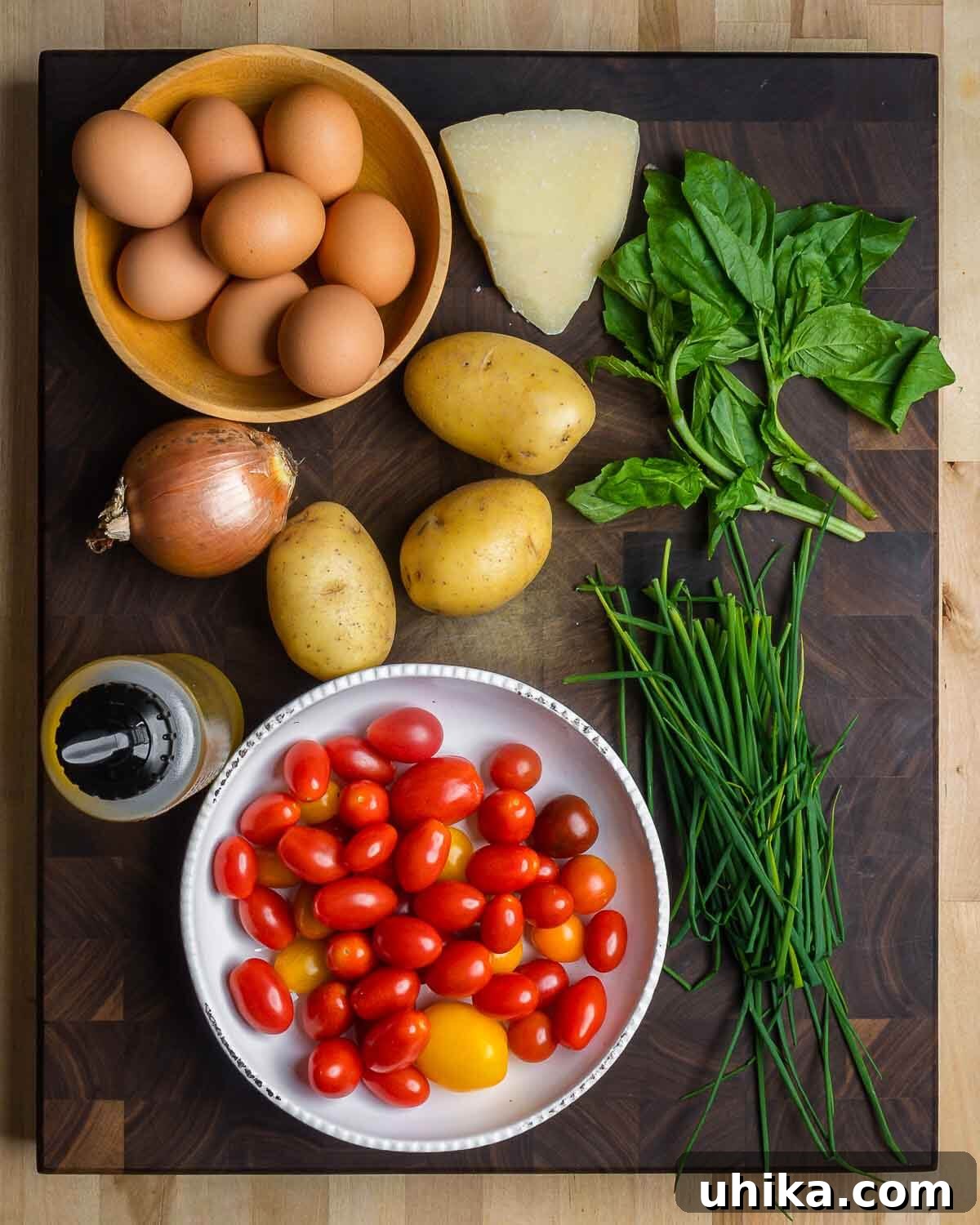 Rustic Potato and Egg Bake 3 A flat lay photograph showcasing the fresh ingredients for a potato frittata: farm-fresh eggs, aromatic Pecorino Romano, vibrant basil, a rustic onion, wholesome potatoes, fragrant chives, and golden olive oil.