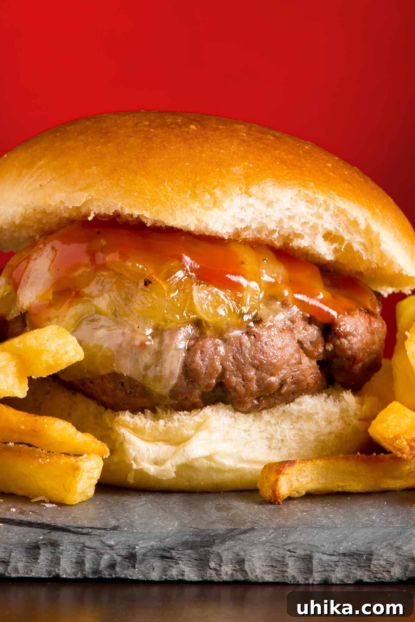 Signature Vermont Cheddar Burgers 2 A vibrant, juicy grilled burger crowned with sweet maple-glazed onions, melted Vermont sharp cheddar cheese, and a dollop of warm maple ketchup, resting on a toasted bun.