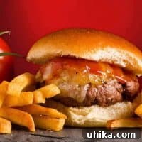 A close-up view of a grilled burger topped with melted cheddar, warm maple ketchup, and sweet glazed onions.