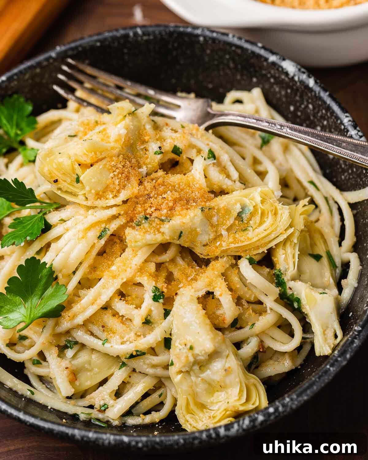Golden Crumb Artichoke Pasta 9 Black plate with linguine, artichoke hearts, and breadcrumbs.