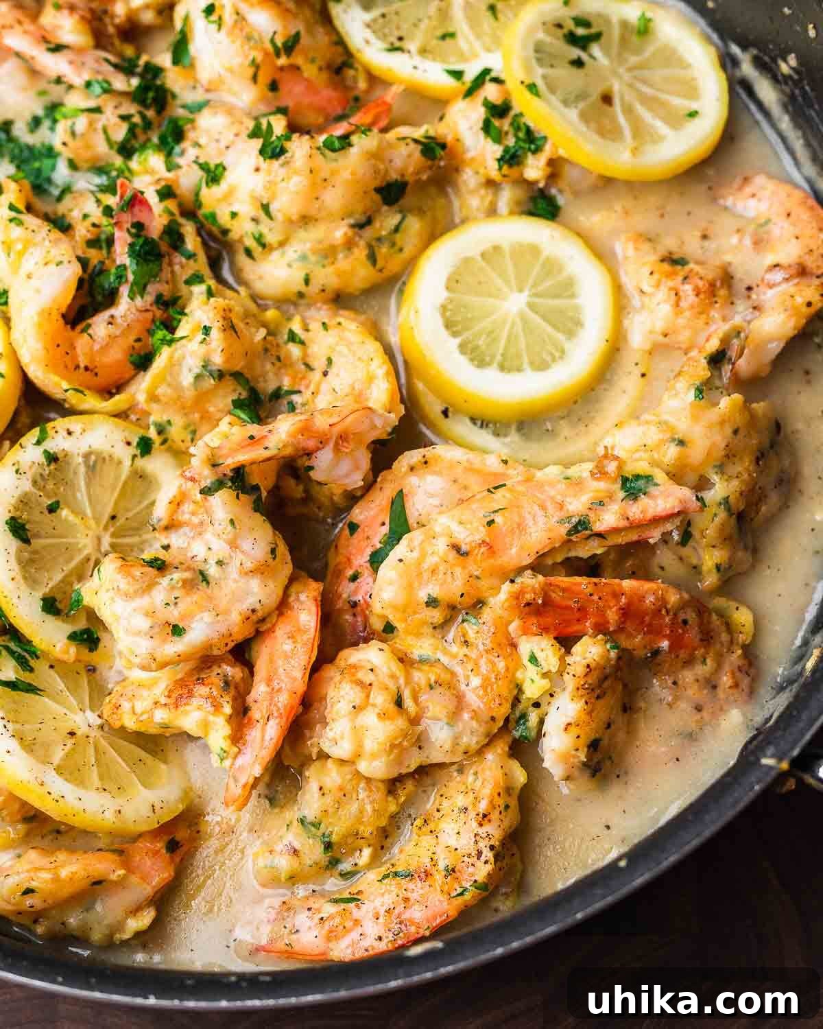 Golden Lemon Butter Shrimp 2 Closeup shot of black pan with shrimp francese, garnished with parsley and lemon slices.