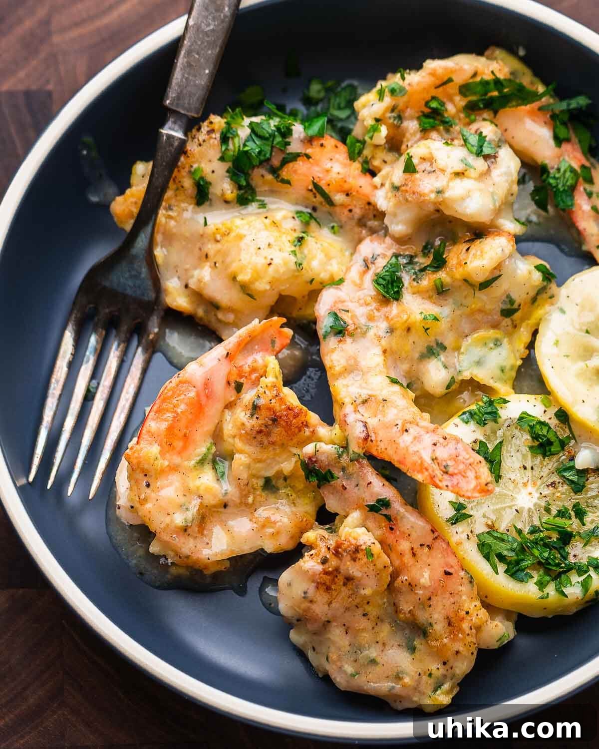 Golden Lemon Butter Shrimp 5 Shrimp francese served in a blue plate with a fork, garnished with lemon and parsley.