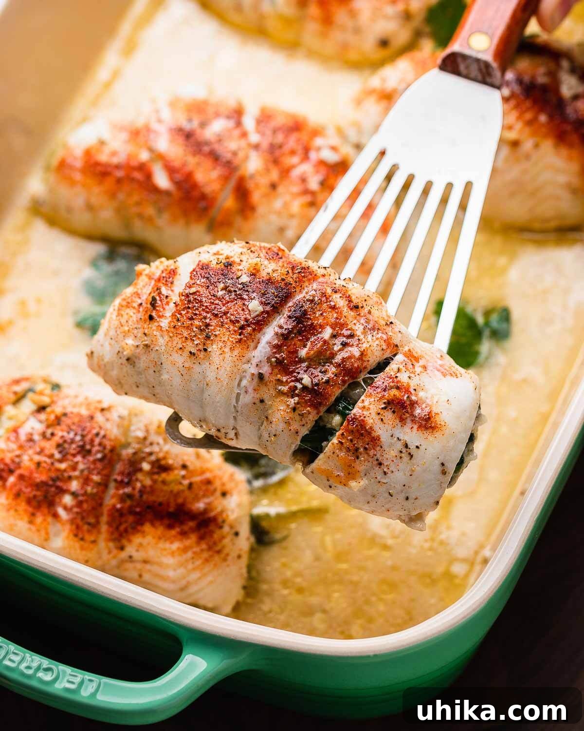 Savory Spinach Stuffed Flounder 2 Spatula holding spinach stuffed flounder above baking dish.