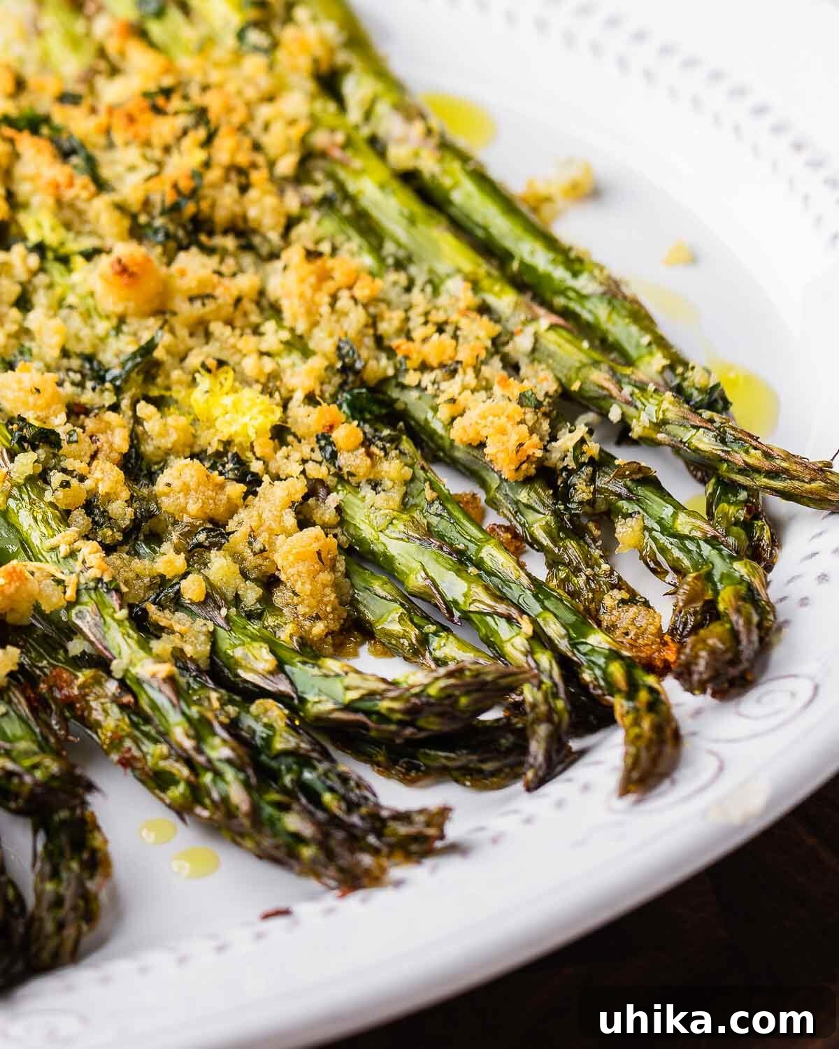 Crispy Parmesan Asparagus Bake 2 Delicious baked asparagus with melted cheese and golden breadcrumbs on a white plate, ready to serve.