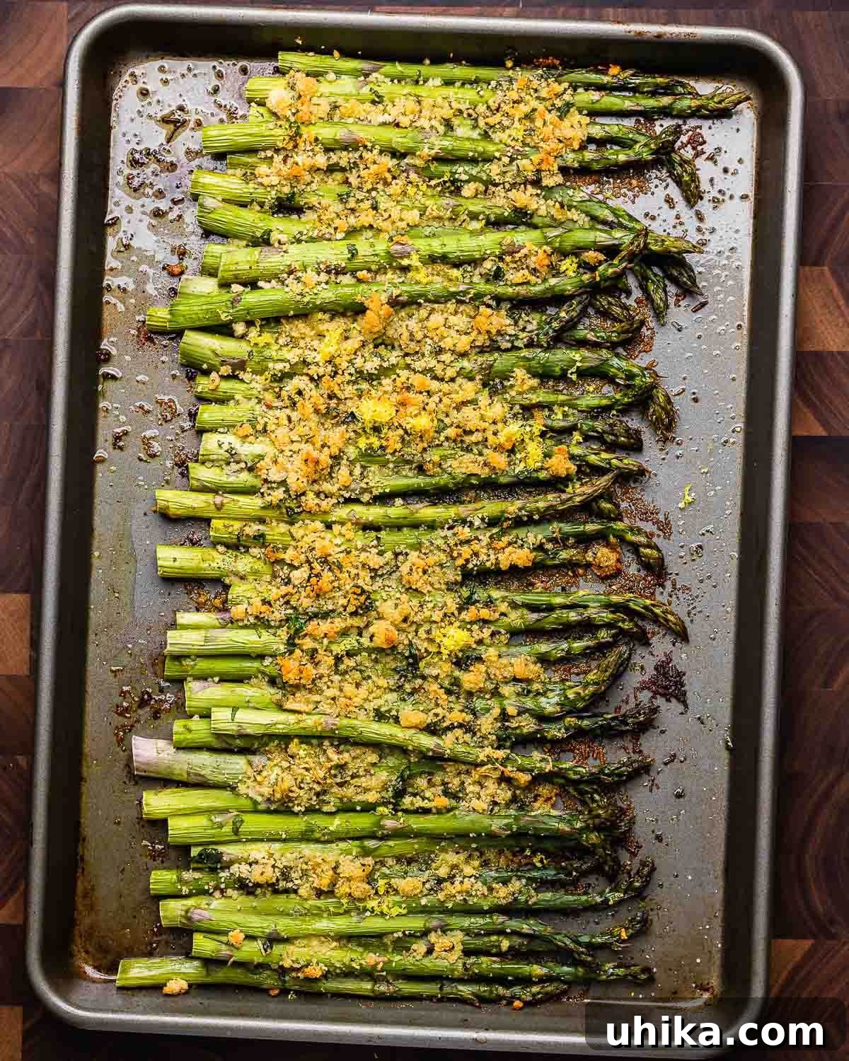 Crispy Parmesan Asparagus Bake 8 Overhead shot of baked asparagus with cheese and breadcrumbs cooking on a baking sheet, golden and tender.