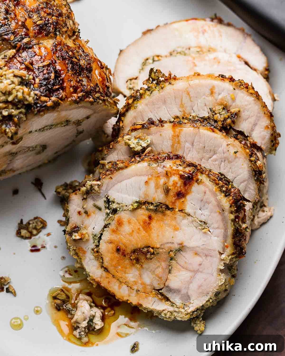 Classic Italian Stuffed Pork Loin 2 Four slices of Italian stuffed pork loin in white platter, showcasing the rich, flavorful stuffing.