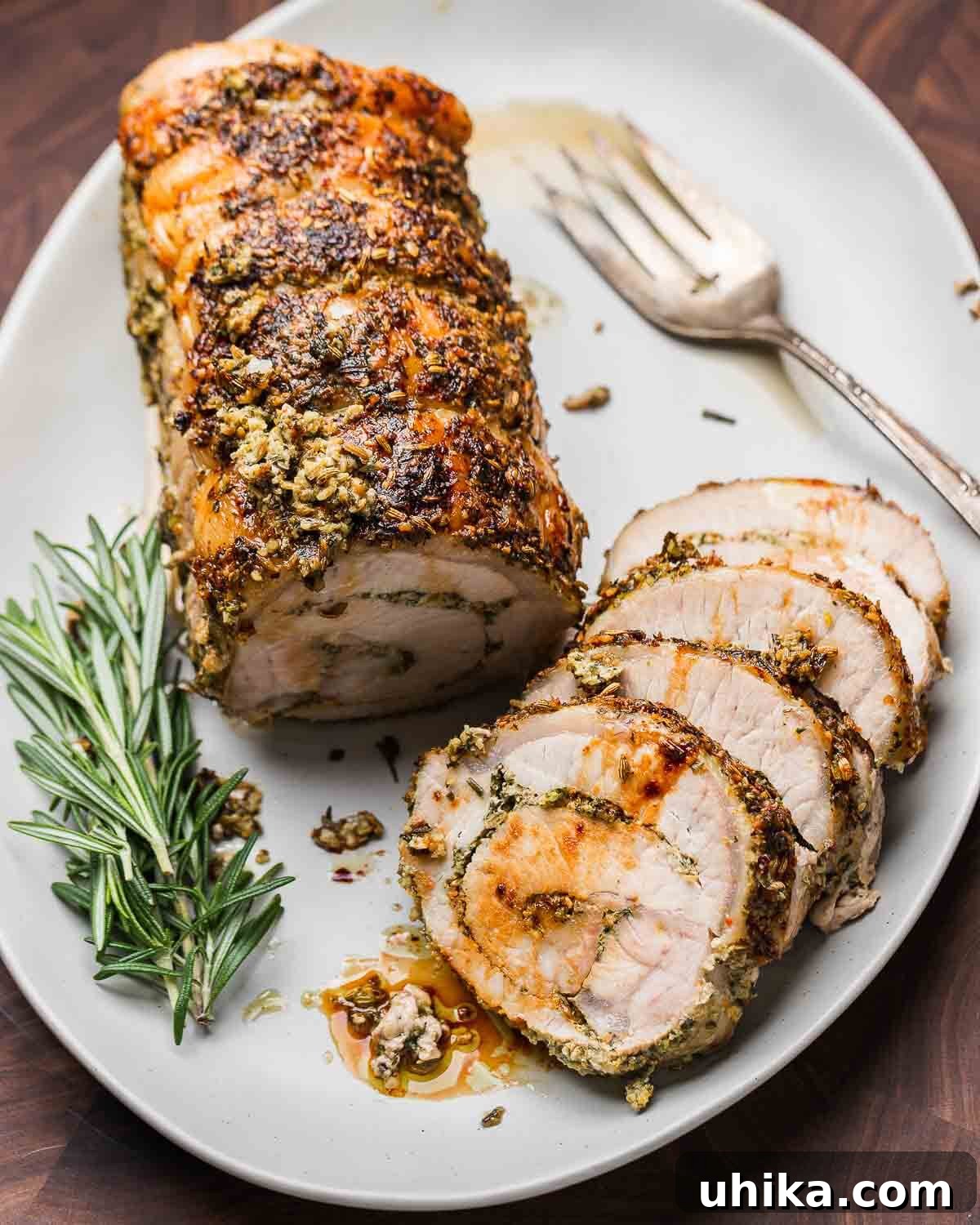 Classic Italian Stuffed Pork Loin 9 Overhead shot of Italian stuffed pork loin on a white platter, perfectly golden and sliced.