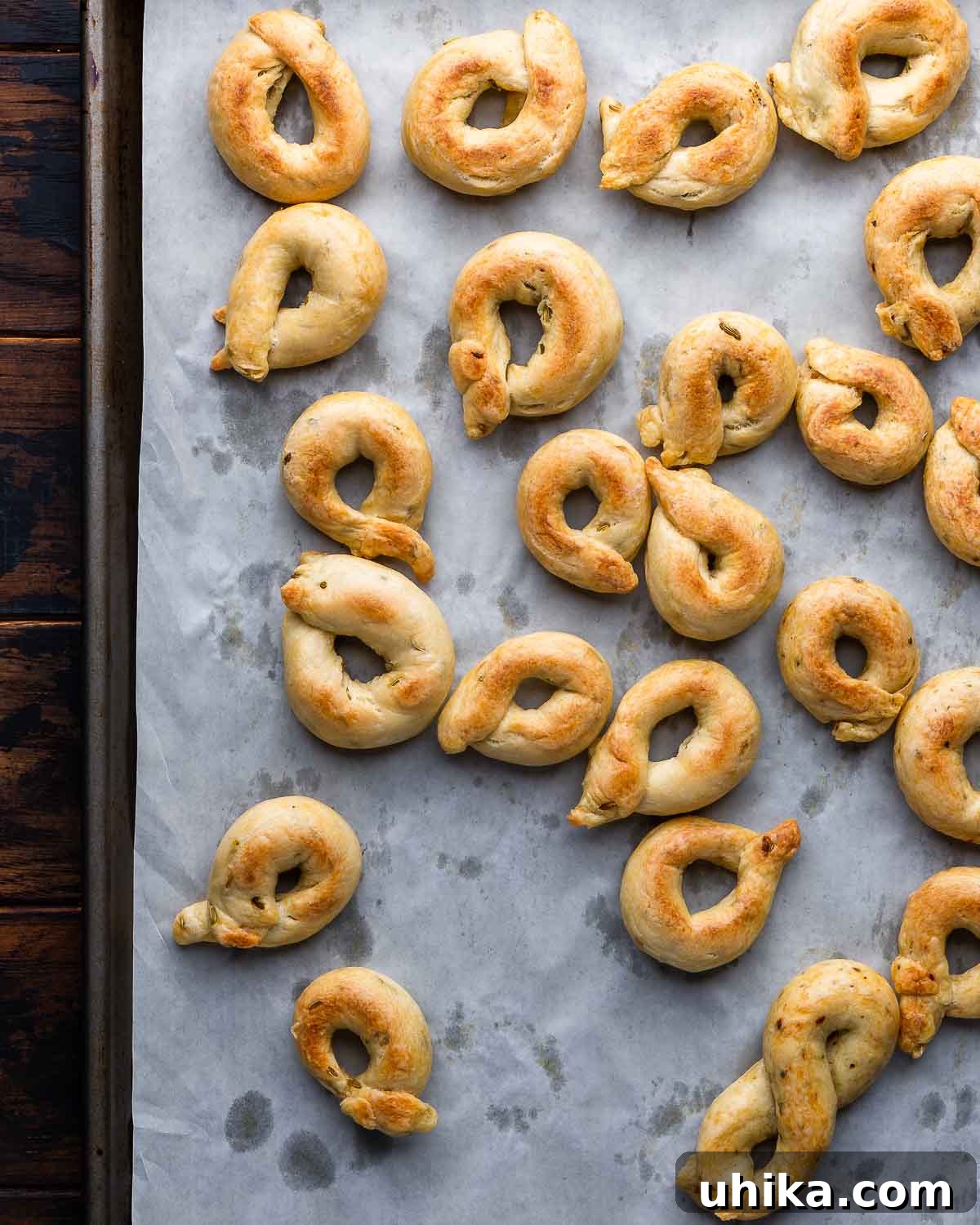 Taralli 8 An overhead shot of a parchment-lined baking sheet filled with perfectly golden, freshly baked taralli.