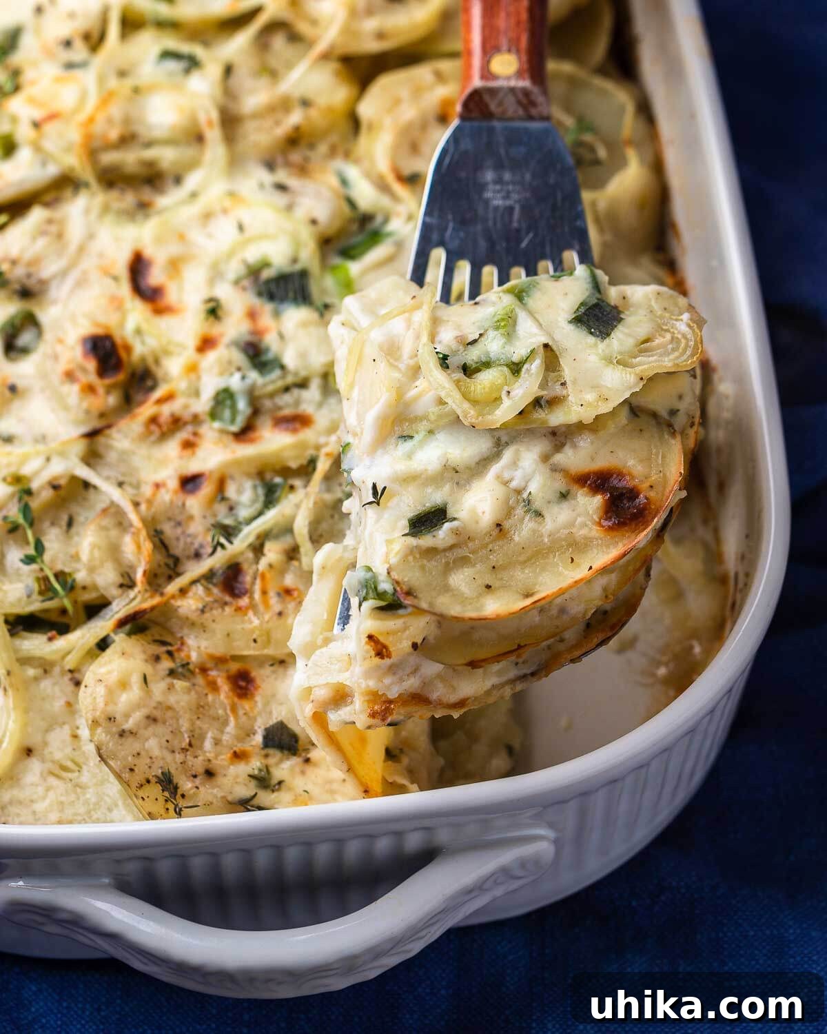 Ultimate Creamy Potato Gratin 8 A spatula lifting a perfect section of creamy, golden scalloped potatoes out of a baking dish, showcasing the layers.