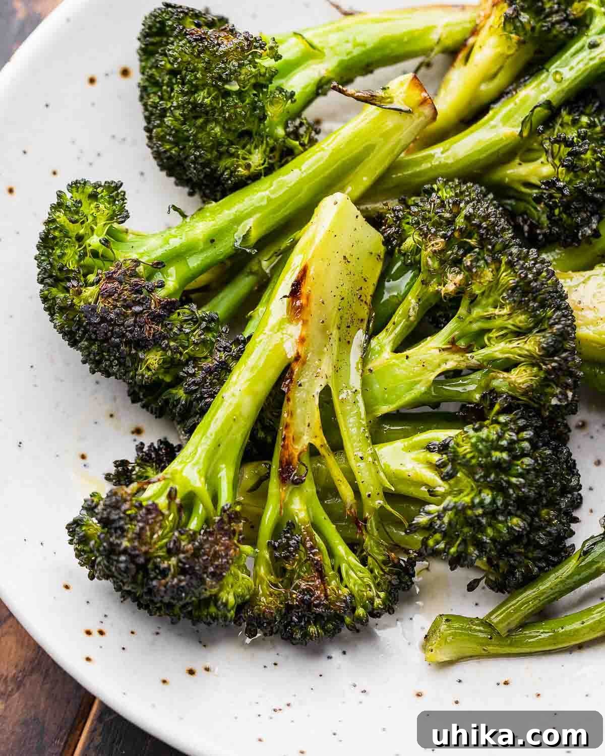 Crispy Roasted Broccoli 6 A close-up shot of perfectly roasted broccoli florets, showcasing their tender texture and slightly charred, caramelized edges, served on a pristine white plate.
