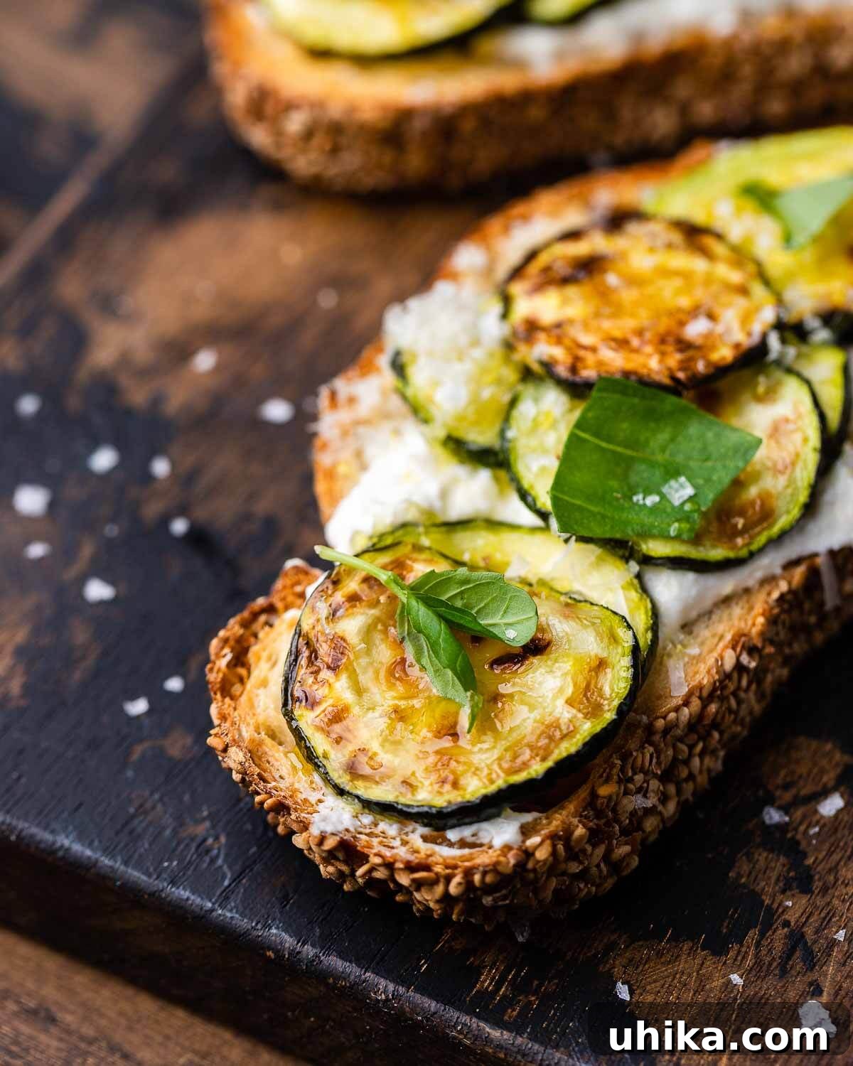 Zucchini Bruschetta Delights 2 Close-up of freshly made Zucchini Bruschetta on a rustic wooden board, showcasing roasted zucchini, lemon ricotta, and basil.