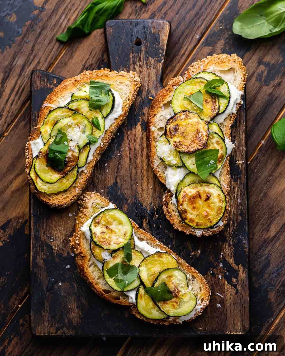 Zucchini Bruschetta Delights 8 An overhead shot of Zucchini Bruschetta pieces artfully arranged on a wooden board, with fresh basil leaves scattered around for garnish.