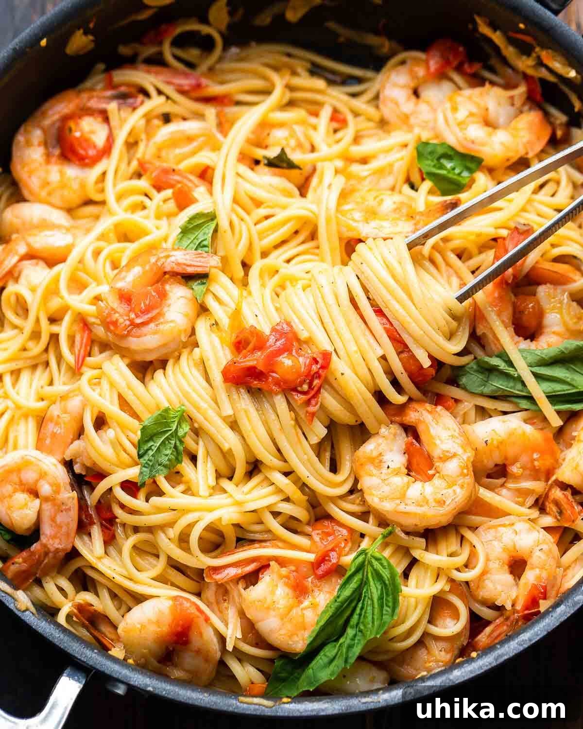 Garlic-Kissed Shrimp Tomato Basil Pasta 2 Freshly prepared Shrimp Tomato Basil Pasta served in a black pan, ready to be dished out with kitchen tweezers.