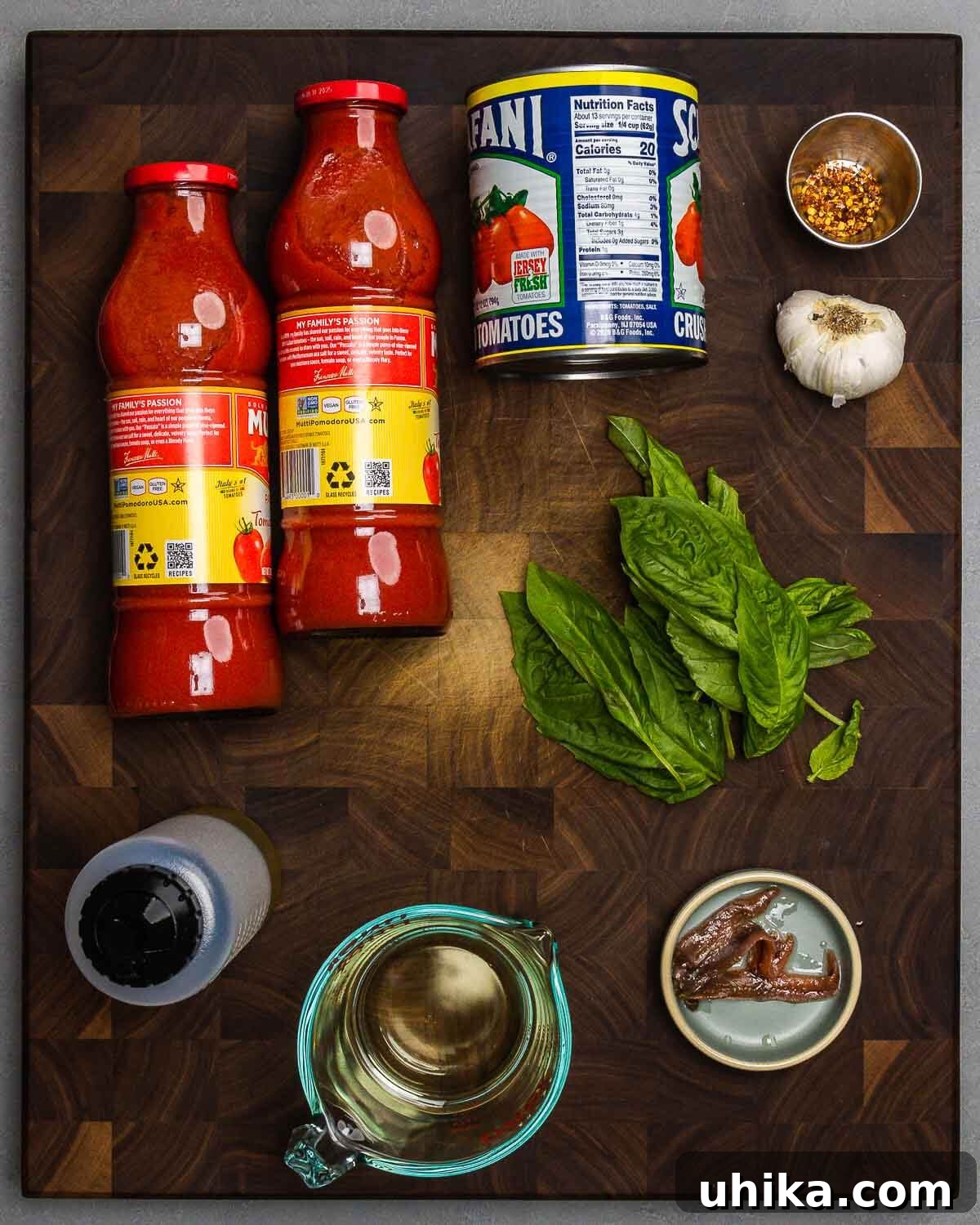 Mama's Meatball Magic 4 A vibrant display of fresh sauce ingredients: smooth passata, rich crushed tomatoes, aromatic garlic, spicy red pepper flakes, golden olive oil, crisp white wine, fragrant basil, and savory anchovies, all ready for cooking.