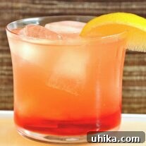 Close-up of a Campari Limoncello Spritzer with lemon garnish in a rounded glass.