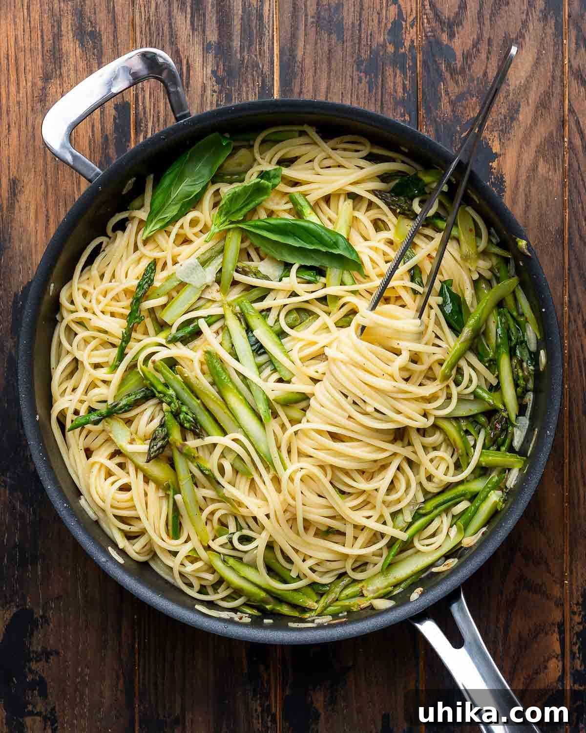 Overhead shot of lemon asparagus pasta on wooden board, garnished with fresh basil.