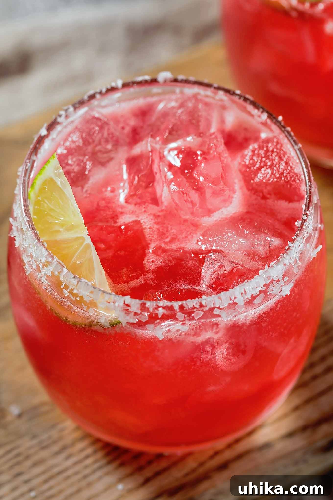 Desert Bloom Margarita 2 A vibrant prickly pear margarita, perfectly chilled over ice in a glass with a crisp salted rim, garnished with a fresh lime wedge. A delicious twist on a classic cocktail.